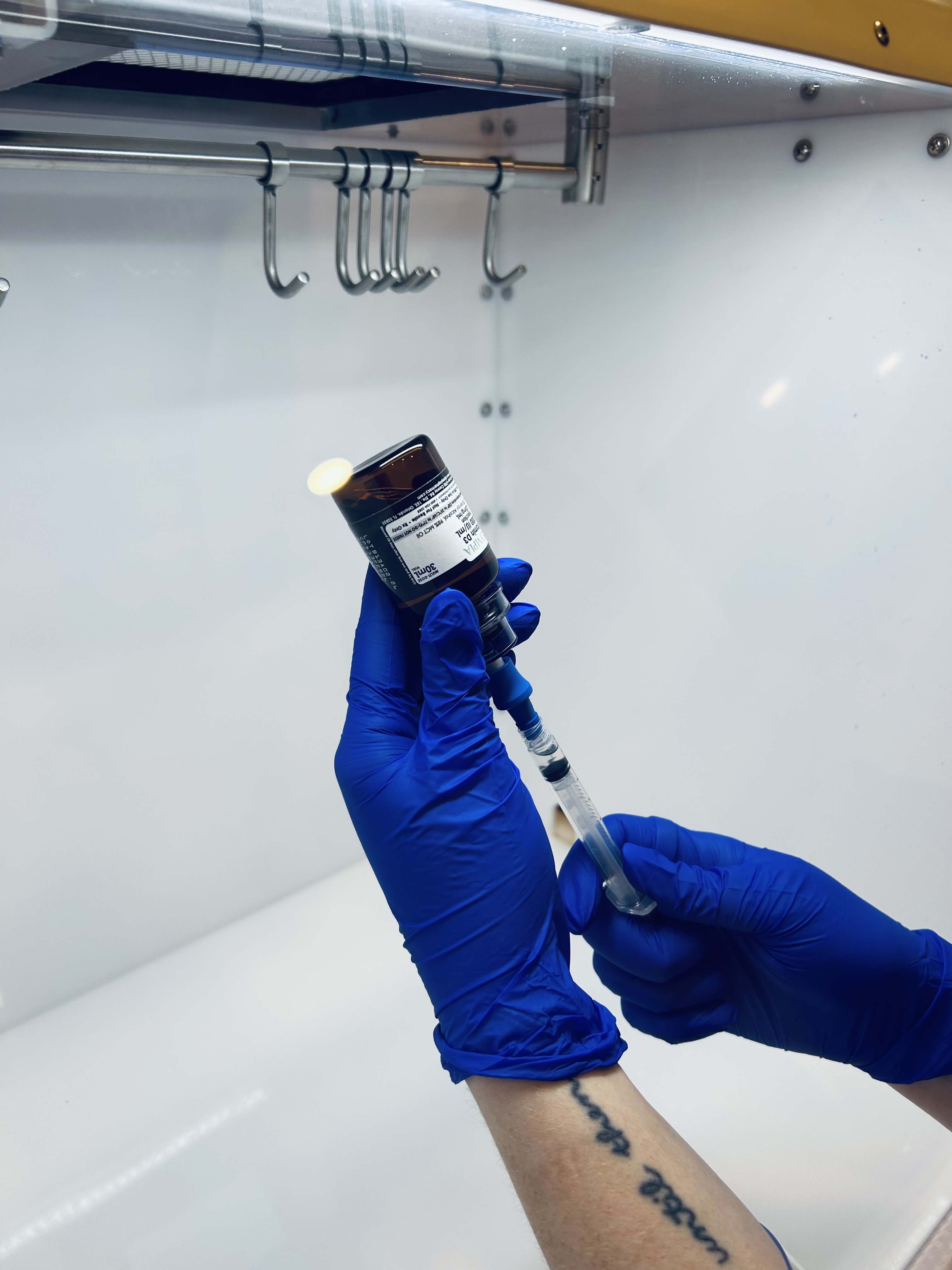 Licensed professional drawing a vitamin compound in a sterile compounding hood