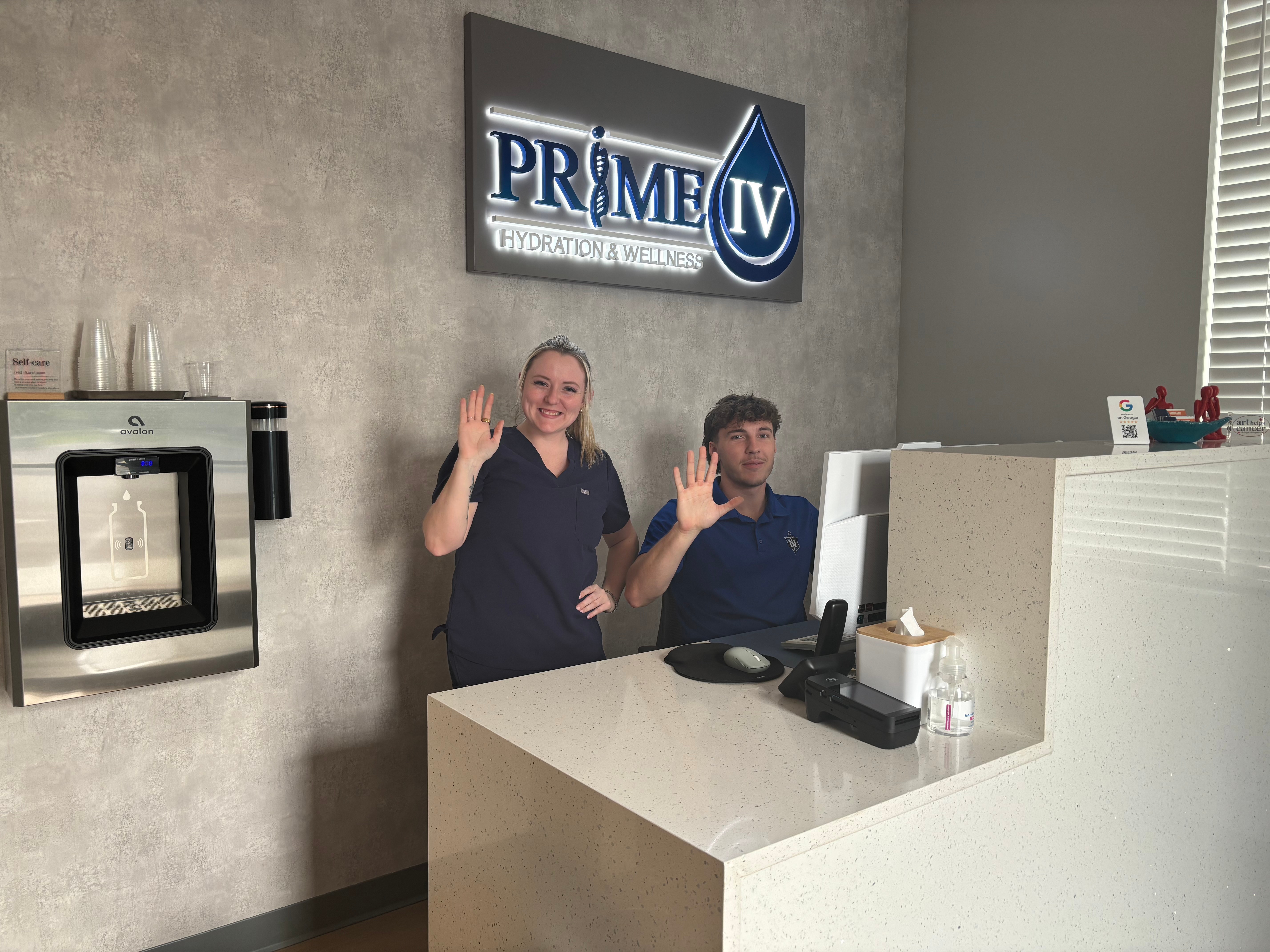 Friendly Prime IV Nolensville staff waving from behind the front desk